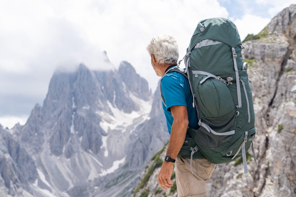 Older man rucking with a loaded backpack in the mountains